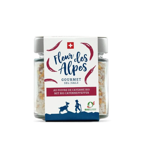 Quadratisches Glas mit "Fleur des Alpes" Gourmet-Salz mit Bio-Cayennepfeffer. Das Etikett ist weiß und rot und zeigt die Schweizer Flagge, rote Cayenneschoten, das BIOSUISSE-Logo sowie eine Ziege und einen Hirten.