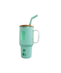 Großer Trinkbecher aus Glas mit mintgrüner Silikonhülle, Holzdeckel, Trinkhalm und seitlichem Griff, vor schwarzem Hintergrund.