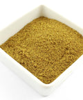 Eine weiße, quadratische Schale gefüllt mit fein gemahlenem gelbbraunem Anispulver.