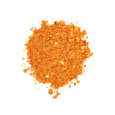 Eine Draufsicht auf einen kleinen Haufen orange-brauner Fajita Mexican Style Gewürzmischung mit grober Textur, sichtbaren Körnchen und kleinen getrockneten Stücken auf weißem Hintergrund.