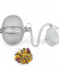 Tee-Ei aus Metallgeflecht mit Kette, klarem Kristall und einem Haufen Kräutertee.