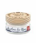 Ein kleines Glasgefäß mit weißem „Fleur des Alpes“ Gourmet-Salz, einem hellen Holzdeckel mit eingraviertem Rundlogo und einem weißen Etikett mit blauen Alpen-Illustrationen.