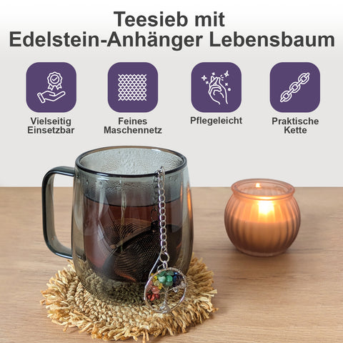 Teesieb mit Edelstein-Lebensbaum-Anhänger in einer Tasse neben einer Kerze.