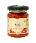 Ein Glas Terra Verde „Pesto Rosso“ mit grünem Deckel. Das Etikett zeigt eine Illustration einer toskanischen Landschaft und frische Tomaten sowie Bio- und Vegan-Siegel.