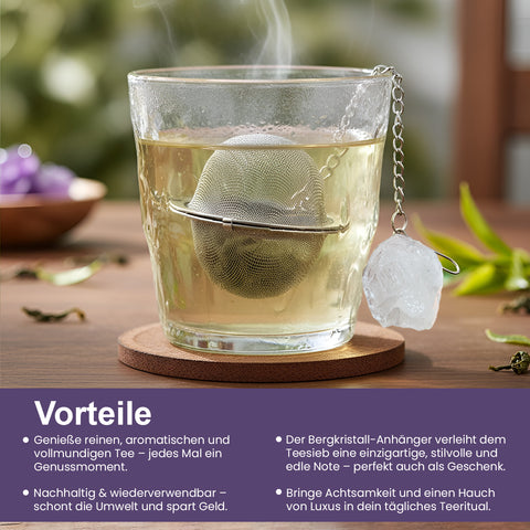 Dampfendes Glas Tee mit einem Netz-Teesieb und Kristall-Anhänger auf einem Untersetzer.