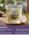 Dampfendes Glas Tee mit Metallsieb und Rosenquarzkristall.