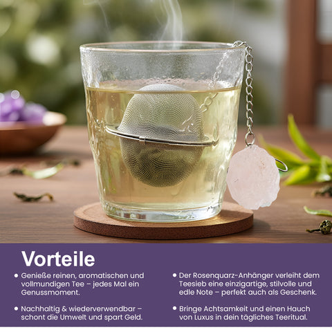 Dampfendes Glas Tee mit Metallsieb und Rosenquarzkristall.