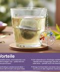 Dampfendes Glas Tee mit Metallsieb und Chakra-Lebensbaum-Anhänger.