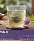 Dampfendes Glas Tee mit Metallsieb und Amethystkristall.