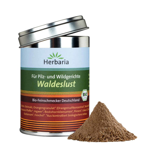 Eine zylindrische Metalldose „Herbaria Waldeslust“ Bio-Gewürz für Pilz- und Wildgerichte, mit leicht geöffnetem Silberdeckel und einem kleinen Häufchen braunem Gewürzpulver daneben.
