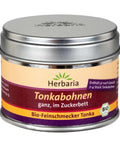 Eine geschlossene silberne Metalldose Herbaria „Tonkabohnen ganz, im Zuckerbett“ mit einem gelb-violetten Etikett und einem Bio-Siegel.