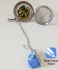 Offenes Teesieb aus Edelstahl mit losem Tee und einem Lapislazuli-Kristall.