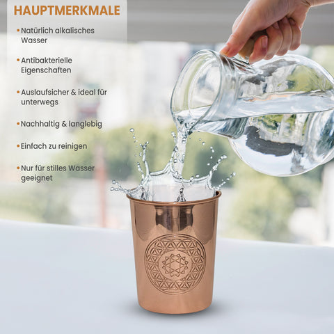 Wasser wird in ein Kupferglas mit Blume des Lebens Design gegossen, was eine Spritzbewegung erzeugt.