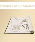 Eine weiße Silikon-Backmatte mit schwarzen Messangaben und dem „Leckerhelfer“-Logo, aufgerollt, um ihre platzsparende Aufbewahrung zu demonstrieren. Der deutsche Text „Platzsparende Aufbewahrung“ steht oben.