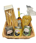 Geflochtener Korb mit Grissini, Pasta, Likör und drei Gewürzdosen.