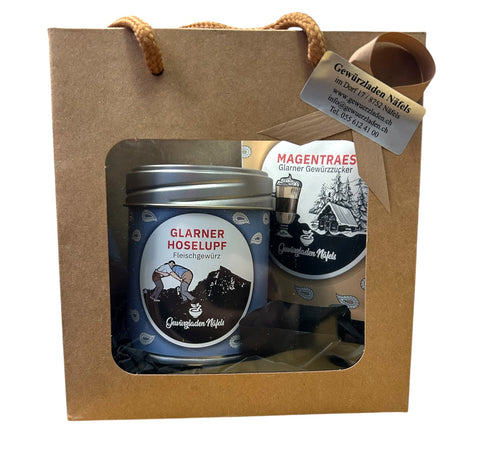 Ein Geschenkkarton vom „Gewürzladen Näfels“ mit einer Dose „Glarner Hoselupf“-Fleischgewürz und einer Packung „Magentraes“-Gewürzzucker.