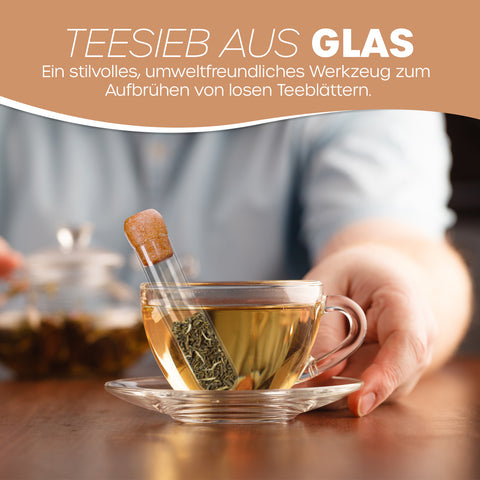 Teefilter aus Glas in Reagenzglasform mit Korken, der lose Teeblätter in einer gefüllten Glastasse aufbrüht.