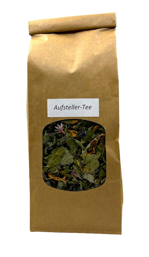 Eine braune Papiertüte mit einem kleinen Sichtfenster, das eine bunte Kräuterteemischung zeigt, beschriftet mit einem weißen Etikett „Aufsteller-Tee“.