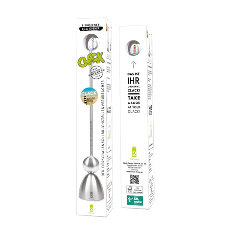 Zwei Seiten der schlanken, weißen Verpackung des "Clack Original" Eieröffners, mit einer Abbildung des silberfarbenen Werkzeugs mit Leuchtturm-Kopf, dem Titel "DER EIERSCHALENSOLLBRUCHSTELLENVERURSACHER" und Herstellerinformationen von Take2-Design.