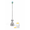 Ein Edelstahl-Eierschalensollbruchstellenverursacher „Clack“ von Take2 Germany mit Führungsstange und glockenförmigem Unterteil sowie einem Keramikkopf mit Bergmotiv, neben einem weichgekochten Ei.