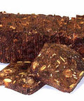 Ein dunkler, rechteckiger Laib geschnittenes „Glarner Früchtebrot“, an dessen Vorderseite zwei dünne Scheiben lehnen, die eine dichte, mit Nüssen und Trockenfrüchten gefüllte Textur zeigen.