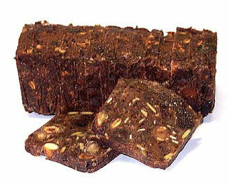 Ein dunkler, rechteckiger Laib geschnittenes „Glarner Früchtebrot“, an dessen Vorderseite zwei dünne Scheiben lehnen, die eine dichte, mit Nüssen und Trockenfrüchten gefüllte Textur zeigen.
