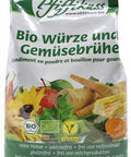 Ein weiß-grüner Nachfüllbeutel „Pfiffikuss Bio Würze und Gemüsebrühe“ mit Bio- und Vegan-Siegeln sowie verschiedenen Illustrationen von frischem Gemüse auf der Vorderseite.
