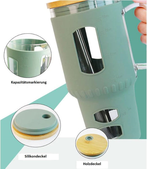 Detailaufnahme eines großen Glasbechers mit mintgrüner Silikonhülle, der Kapazitätsmarkierungen und separate Aufnahmen des Silikondeckels und des Holzdeckels zeigt.
