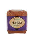 Ein Klarsichtbeutel mit rötlich-braunem Gewürzpulver der Marke Gwürzhüsli, beschriftet mit „Harissa Bizarro“ auf einem violett-cremefarbenen Etikett.