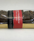 Ein Glarner Früchtebrot in Klarsichtverpackung mit rot-schwarzer Banderole, die auf die Herstellung ohne Zuckerzusatz sowie enthaltene Haselnüsse, Mandeln und Baumnüsse hinweist.