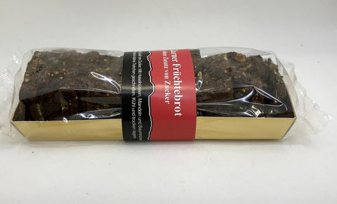 Ein Glarner Früchtebrot in Klarsichtverpackung mit rot-schwarzer Banderole, die auf die Herstellung ohne Zuckerzusatz sowie enthaltene Haselnüsse, Mandeln und Baumnüsse hinweist.