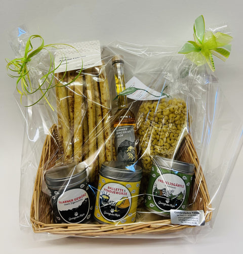 Als Geschenk verpackter Korb mit Grissini, Likör, Pasta und drei Gewürzdosen.