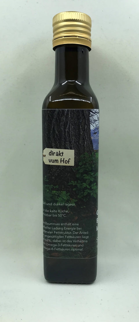 Seitenansicht einer Glasflasche „Glarner Baumnuss-Öl“, die ein regionales „Glarnerland regio.garantie“-Siegel mit rotem Bergsymbol sowie zusätzliche Produktinformationen auf dem rückseitigen Etikett zeigt.