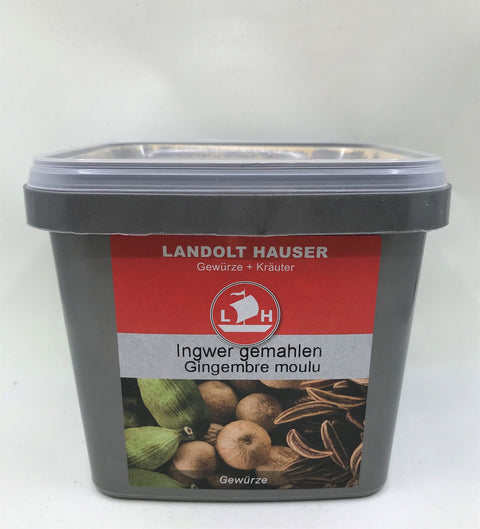 Ein quadratischer grauer Kunststoffbehälter mit „Ingwer gemahlen“ von Landolt Hauser, mit einem roten Etikett, Segelschiff-Logo und einer Abbildung von Ingwerwurzeln und grünen Kardamomkapseln.