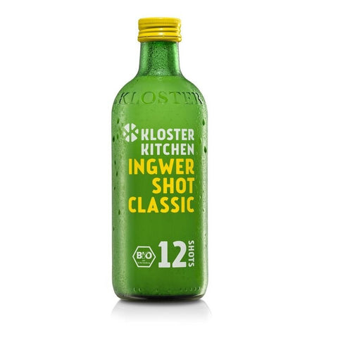 Eine grüne Glasflasche „Kloster Kitchen Ingwer Shot Classic“ mit gelbem Verschluss, beschriftet mit „12 Shots“ (360ml) und einem weißen Bio-Siegel.