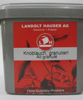 Ein großer, grauer Kunststoff-Vorratsbehälter für Knoblauch granuliert von Landolt Hauser AG mit rotem Etikett, Segelschiff-Logo und transparentem Deckel.
