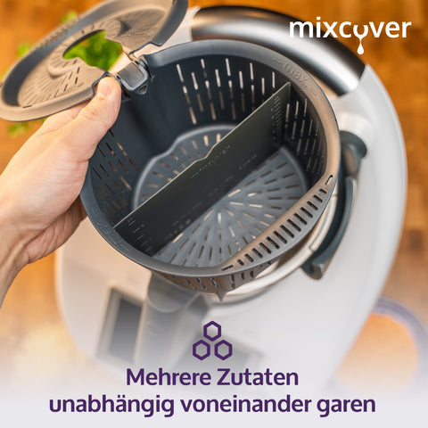 Eine Hand hält den Thermomix Garkorb (Varoma-Einsatz) mit dem eingesetzten dunkelgrauen mixcover Silikon-Teiler, was die Möglichkeit zeigt, mehrere Zutaten unabhängig voneinander zu garen. Text: „Mehrere Zutaten unabhängig voneinander garen“.