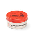 Eine 100-ml-Silberdose der wärmenden „puralpina Murmeli-Kräutersalbe“ mit einem leuchtend roten Deckel, auf dem die Illustration eines Murmeltiers abgebildet ist.