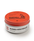 Eine 50-ml-Silberdose der wärmenden „puralpina Murmeli-Kräutersalbe“ mit einem leuchtend roten Deckel, auf dem die Illustration eines Murmeltiers abgebildet ist.
