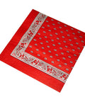Eine einzelne rote Papierserviette mit einer klassischen weiß-schwarzen Paisley-Bordüre und einem wiederkehrenden Tropfenmuster in der Mitte.
