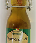 Eine klare Bügelflasche aus Glas, gefüllt mit gelbem Peperonciniöl und einer ganzen getrockneten Chilischote, versehen mit einem grün-beigen „Gwürzhüsli“-Etikett.