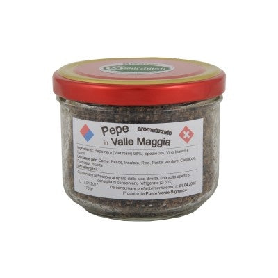 Ein klares Glas mit rotem Deckel, gefüllt mit „Pepe Valle Maggia“, einer dunklen, groben Pfeffermischung aus der Schweiz, mit einem weißen Etikett und technischen Produktdetails auf Italienisch.