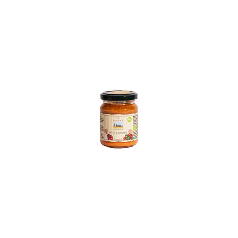 Ein kleines Glas mit Terra Verde Pesto Calabrese, das die rot-orangefarbene Paste im Inneren und ein Etikett mit einer kleinen Hof-Illustration zeigt.