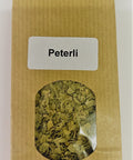 Eine braune Papiertüte mit einem kleinen Sichtfenster, das getrocknete grüne Petersilienflocken zeigt, beschriftet mit einem weißen Etikett „Peterli“.