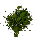Ein kleiner Haufen getrockneter, leuchtend grüner Pfefferminzblätter, die auf einem schlichten weißen Hintergrund verstreut sind.