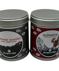 Zwei Gewürzdosen stehen nebeneinander: links eine schwarze Dose "Glarner Gewürz usem Zigerschlitz" und rechts eine rot-schwarze Dose "Glühwein Gewürzmischung".