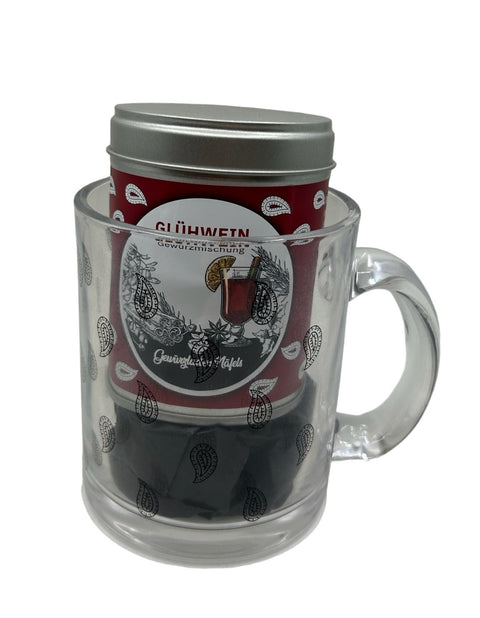 Eine rote Glühwein Gewürzdose in einem durchsichtigen Glasbecher mit Paisley-Muster.
