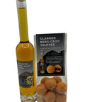 Eine hohe, schlanke Glasflasche „Glarner Berg-Geist Likör“ mit Korkverschluss, neben einer Klarsichttüte mit orange bestäubten „Glarner Berg-Geist Truffes“.