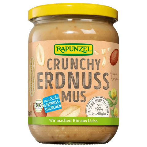 Glas "Rapunzel Crunchy Erdnuss Mus" (Bio Erdnussmus mit Salz & Erdnussstückchen) mit gelbem Deckel und beigem Etikett, auf dem Erdnüsse und ein grünes Bio-Siegel abgebildet sind.