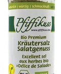 Ein durchsichtiger Gewürzstreuer aus Glas mit schwarzem Deckel, befüllt mit „Pfiffikuss Bio Premium Kräutersalz Salatgenuss“, einer Bio-Kräutersalzmischung mit Bio- und Vegan-Siegeln auf dem Etikett.